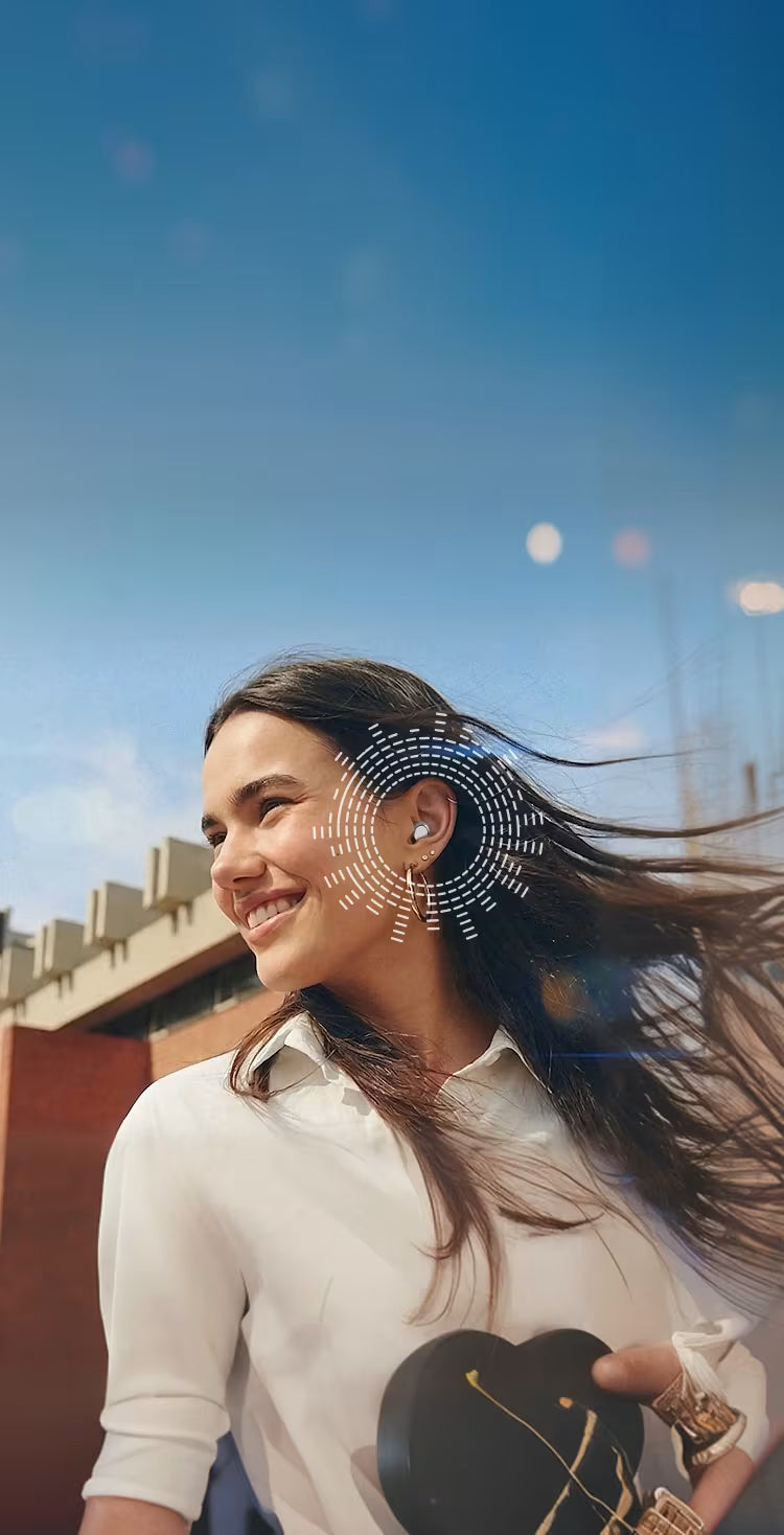 Woman with long hair smiling outdoors against a blue sky.